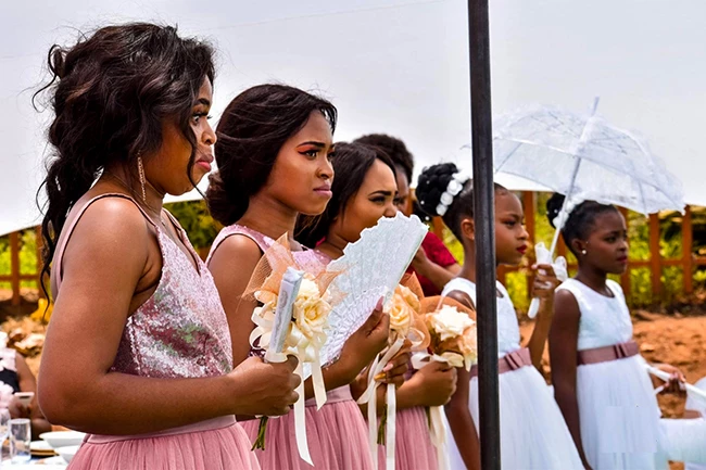 Bride and groom strolling hand-in-hand outside wedding tent during celebratio