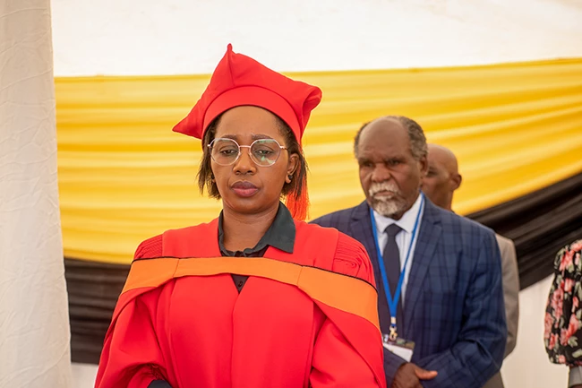 Smiling graduate posing with friends in academic regalia